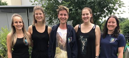 Fünf Jugenrotkreuzler:innen, vier Mädchen und ein Junge in der Mitte vor einem Baum und einer Hecke.